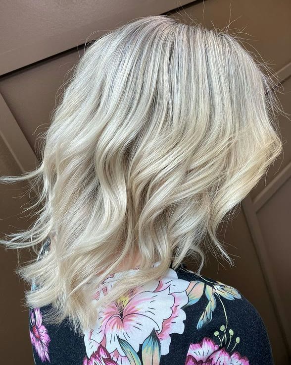 Wavy blonde lob with a soft shadow root, seen from behind