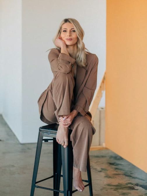Inna Chihoial, owner of Inna Hair Studio, seated on a stool in a bright studio