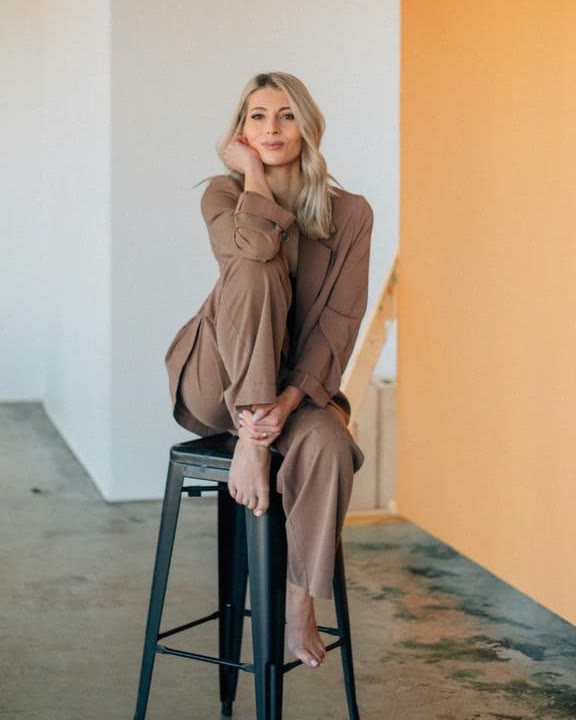 Inna Chihoial, owner of Inna Hair Studio, seated on a stool in a bright studio