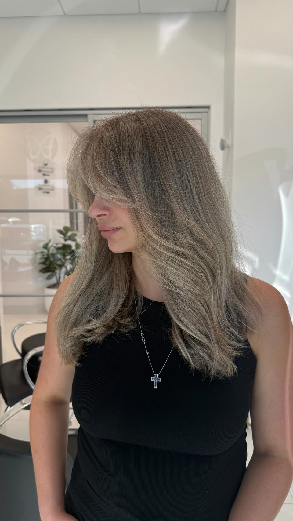 Long, ash-toned light-brown hair with lighter pieces and face-framing layers, seen from the side
