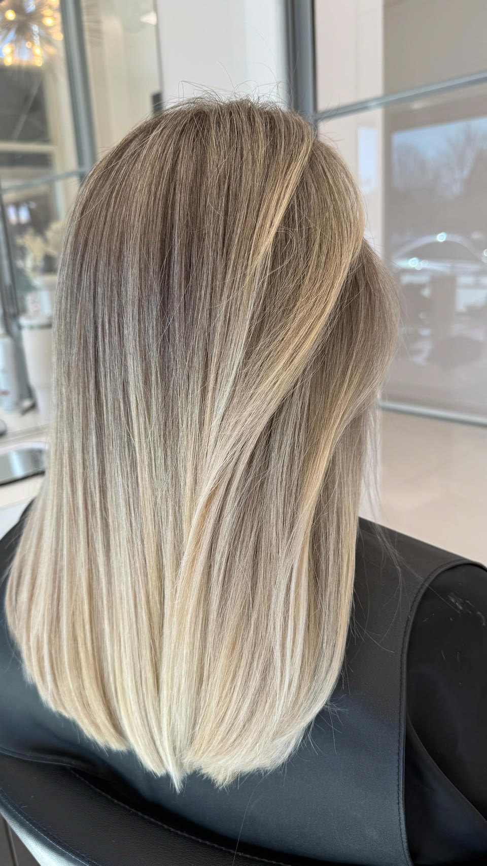 Straight, medium-length hair with a soft shadow root blending into bright blonde ends