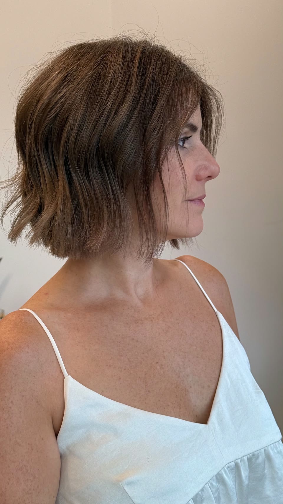 Chin-length, textured brunette bob with soft movement, seen in profile