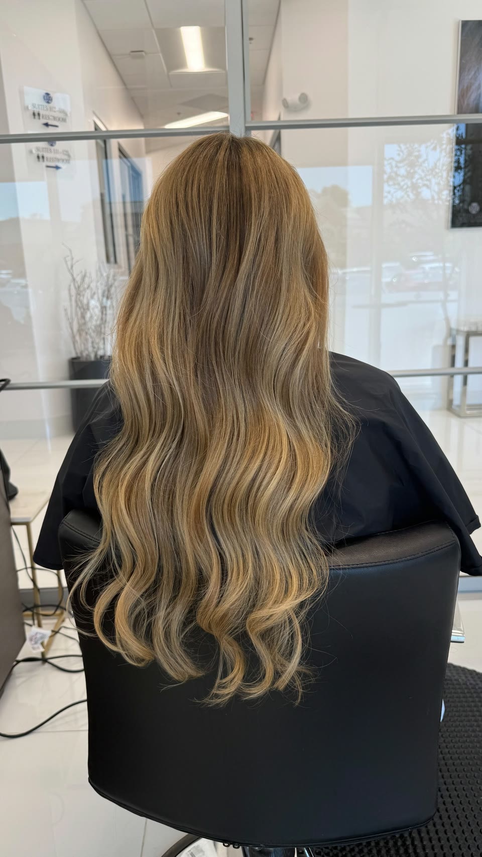 Long golden-blonde balayage in loose curls, seen from behind