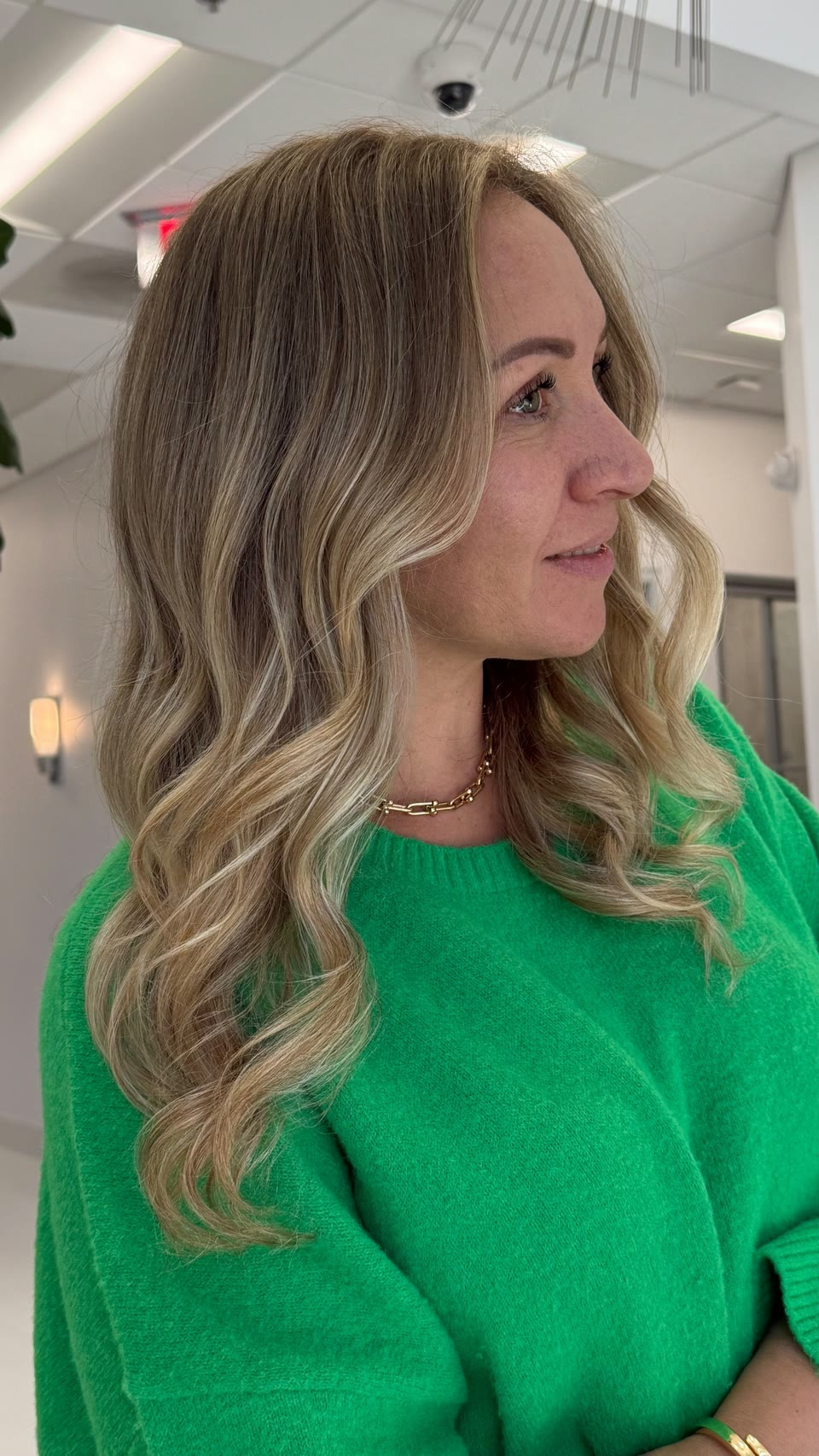 Honey-blonde balayage waves with a soft root, seen in profile